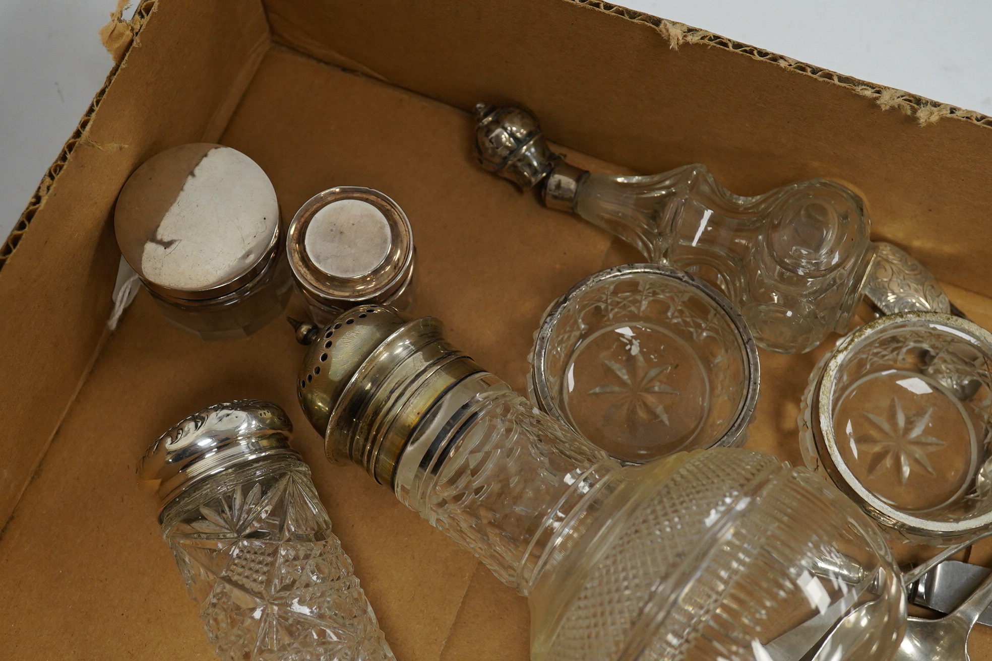 Five assorted silver topped toilet jars, a pair of silver mounted glass salts, a late Victorian repousse silver oval pill box, two modern silver pill boxes, four silver spoons, a silver handled knife, a pair of silver ha